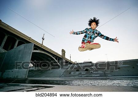 Picture - Asian man break dancing under overpass. Fotosearch