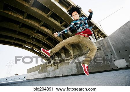 Stock Image - Asian man break dancing under overpass. Fotosearch