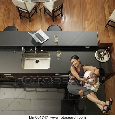 Stock Photo - Asian man carrying wife in kitchen. Fotosearch