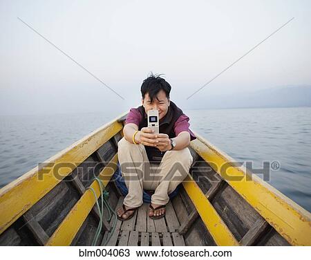 Asian man on boat taking photograph with cell phone View Large Photo Image Stock Image - Asian man on boat taking photograph with cell phone. Fotosearch