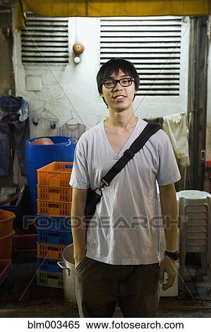 Stock Photography - Asian man standing in alley. Fotosearch