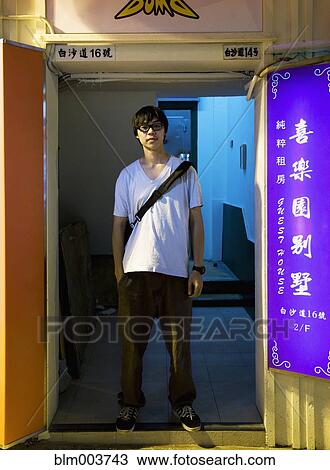 Stock Image - Asian man standing in doorway. Fotosearch