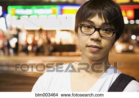 Picture - Asian man standing on urban street. Fotosearch