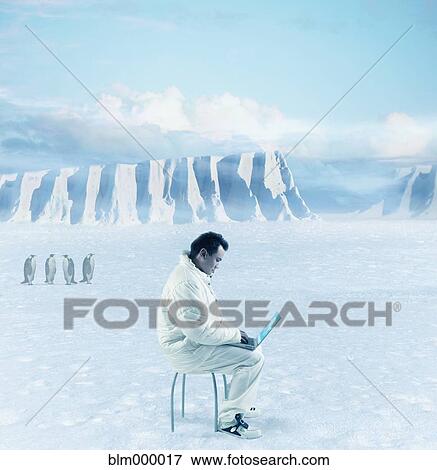 Stock Photo - Asian man typing on laptop next to penguins. Fotosearch