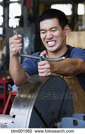 Stock Image - Asian man working with metal in warehouse. Fotosearch