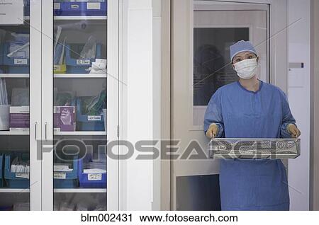 Stock Image - Asian medical professional carrying surgical tools. Fotosearch