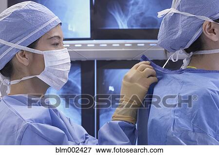 Asian medical professional fastening coworker's gown View Large Photo Image Stock Photo - Asian medical professional fastening coworker's gown. Fotosearch