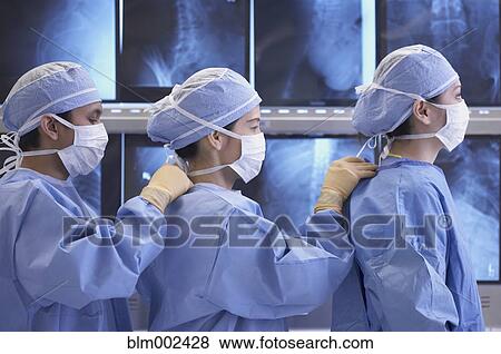 Stock Photo - Asian medical professionals fastening coworkers' gowns. Fotosearch