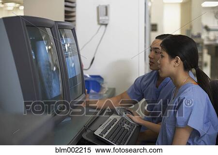 Stock Photography - Asian medical professionals looking at computer. Fotosearch