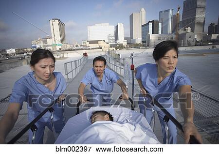 Stock Photo - Asian medical professionals pushing patient in gurney . Fotosearch
