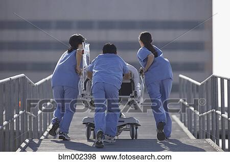 Stock Photo - Asian medical professionals pushing gurney on roof . Fotosearch