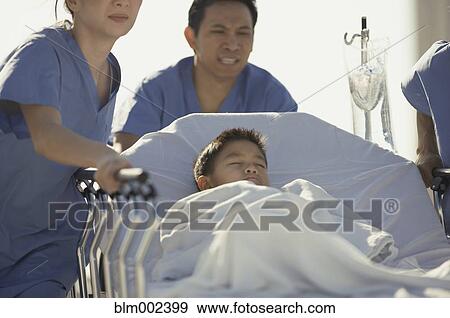 Stock Photo - Asian medical professionals pushing patient in gurney . Fotosearch