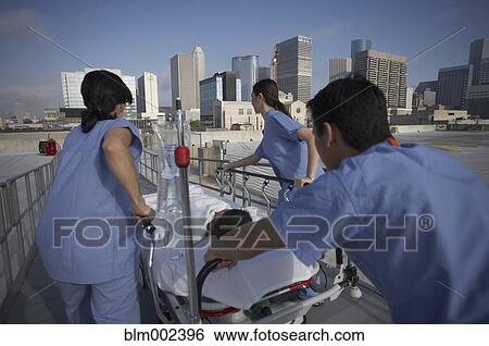 Asian medical professionals pushing patient in gurney View Large Photo Image Stock Photograph - Asian medical professionals pushing patient in gurney . Fotosearch