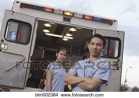 Picture - Asian medical professionals standing at back of ambulance. Fotosearch