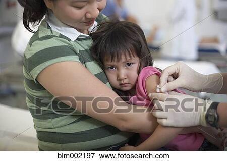 Stock Photo - Asian mother hugging daughter at hospital. Fotosearch