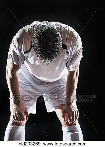 Stock Photo - Asian soccer player resting indoors. Fotosearch