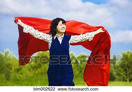Stock Image - Asian woman holding blanket in wind. Fotosearch