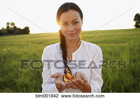 Stock Image - Asian woman holding butterfly in hands. Fotosearch