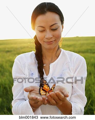 Stock Image - Asian woman holding butterfly in hands. Fotosearch