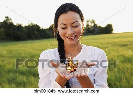 Stock Photography - Asian woman holding butterfly in hands. Fotosearch