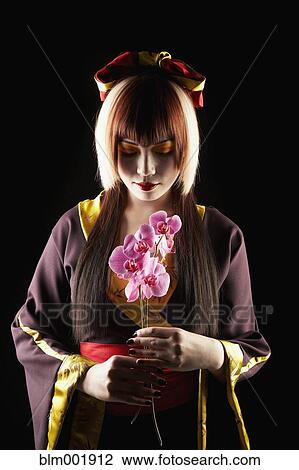 Asian woman in traditional clothing holding flower View Large Photo Image Stock Image - Asian woman in traditional clothing holding flower. Fotosearch