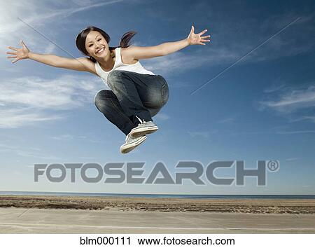 Stock Image - Asian woman jumping in air. Fotosearch