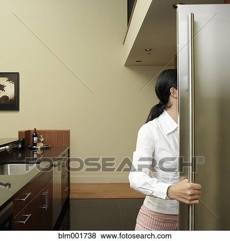 Stock Photo - Asian woman looking in refrigerator. Fotosearch