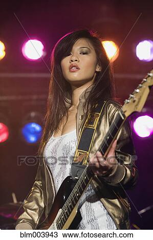 Asian woman playing electric guitar onstage View Large Photo Image Stock Image - Asian woman playing electric guitar onstage. Fotosearch