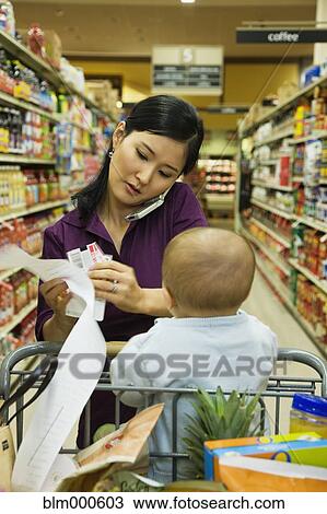 Asian woman reading list in grocery store View Large Photo Image Stock Image - Asian woman reading list in grocery store. Fotosearch