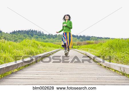 Asian woman running on wooden path View Large Photo Image Stock Photo - Asian woman running on wooden path. Fotosearch