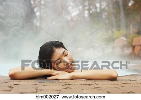 Stock Photo - Asian woman sitting in hot tub. Fotosearch