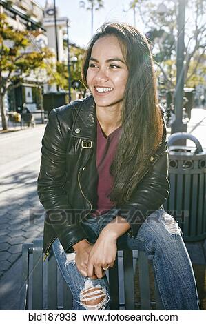 Stock Photo - Asian woman sitting on city bench. Fotosearch