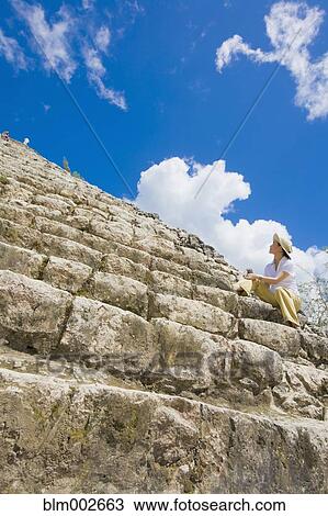 Stock Image - Asian woman sitting on Mayan temple steps. Fotosearch