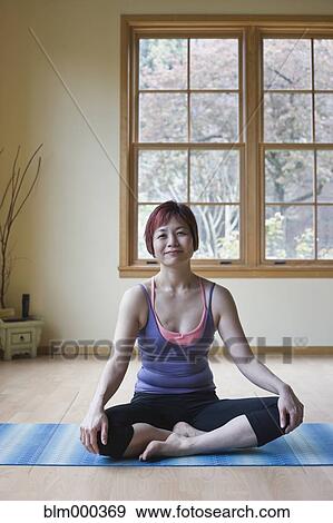 Stock Photo - Asian woman sitting on yoga mat. Fotosearch