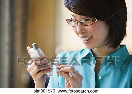 Stock Image - Asian woman smiling and using electronic organizer. Fotosearch