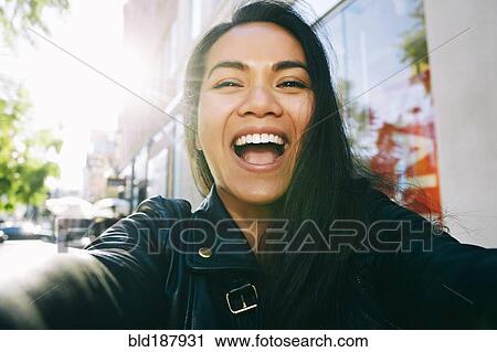 Stock Image - Asian woman smiling outdoors. Fotosearch