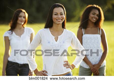 Asian woman standing in meadow with friends in the background View Large Photo Image Picture - Asian woman standing in meadow with friends in the background. Fotosearch