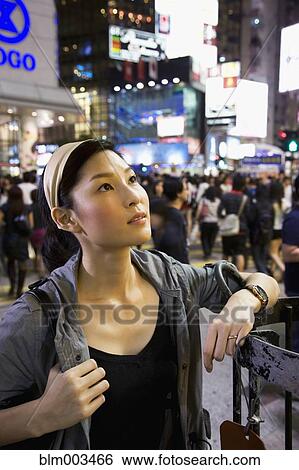 Stock Photograph - Asian woman standing on crowded urban street. Fotosearch