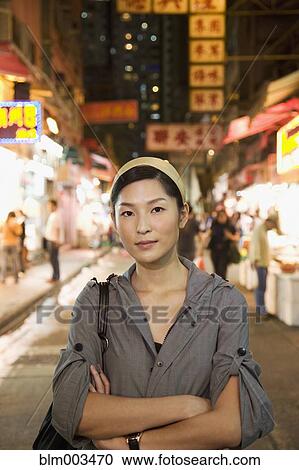 Stock Image - Asian woman standing on urban street. Fotosearch