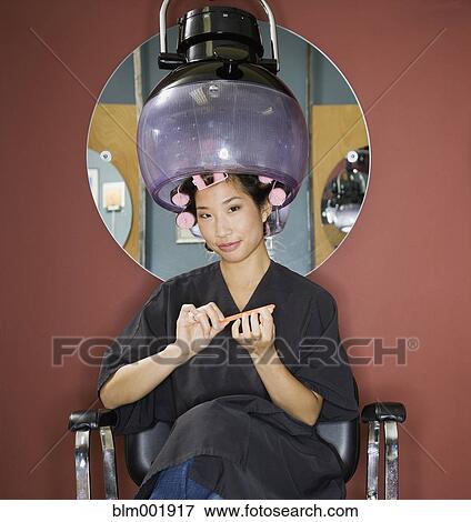Stock Photo - Asian woman under hair dryer in salon. Fotosearch