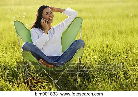 Stock Image - Asian woman using cell phone in meadow. Fotosearch
