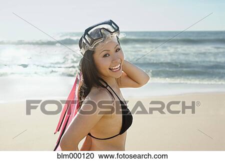 Stock Image - Asian woman wearing goggles at beach. Fotosearch