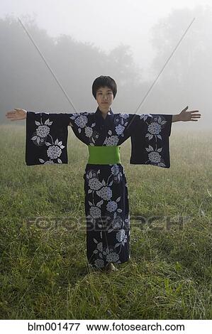 Stock Photo - Asian woman wearing traditional robe standing in field. Fotosearch