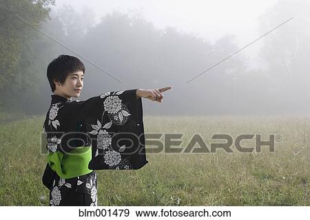 Stock Photo - Asian woman wearing traditional robe standing in field. Fotosearch