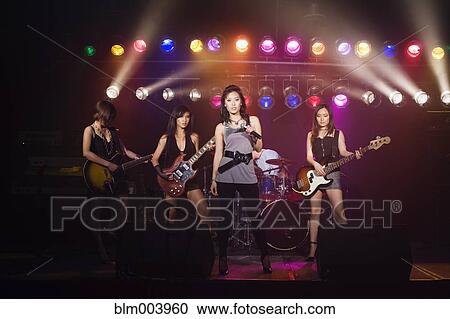 Stock Image - Asian women singing and playing electric guitar onstage. Fotosearch