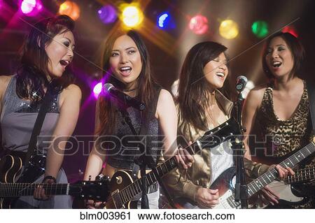 Stock Image - Asian women singing and playing electric guitar onstage. Fotosearch