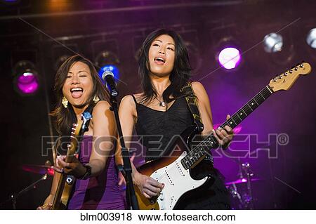 Stock Photo - Asian women singing and playing electric guitar onstage. Fotosearch