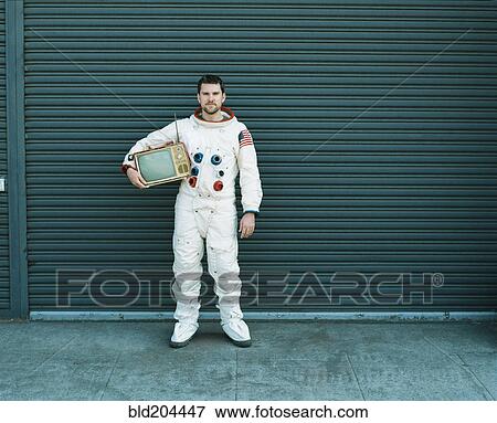 Astronaut carrying television on city street View Large Photo Image Stock Photo - Astronaut carrying television on city street. Fotosearch