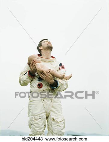 Stock Photo - Astronaut holding baby outdoors. Fotosearch