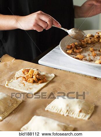 Stock Image - Baker filling miniature apple pies. Fotosearch